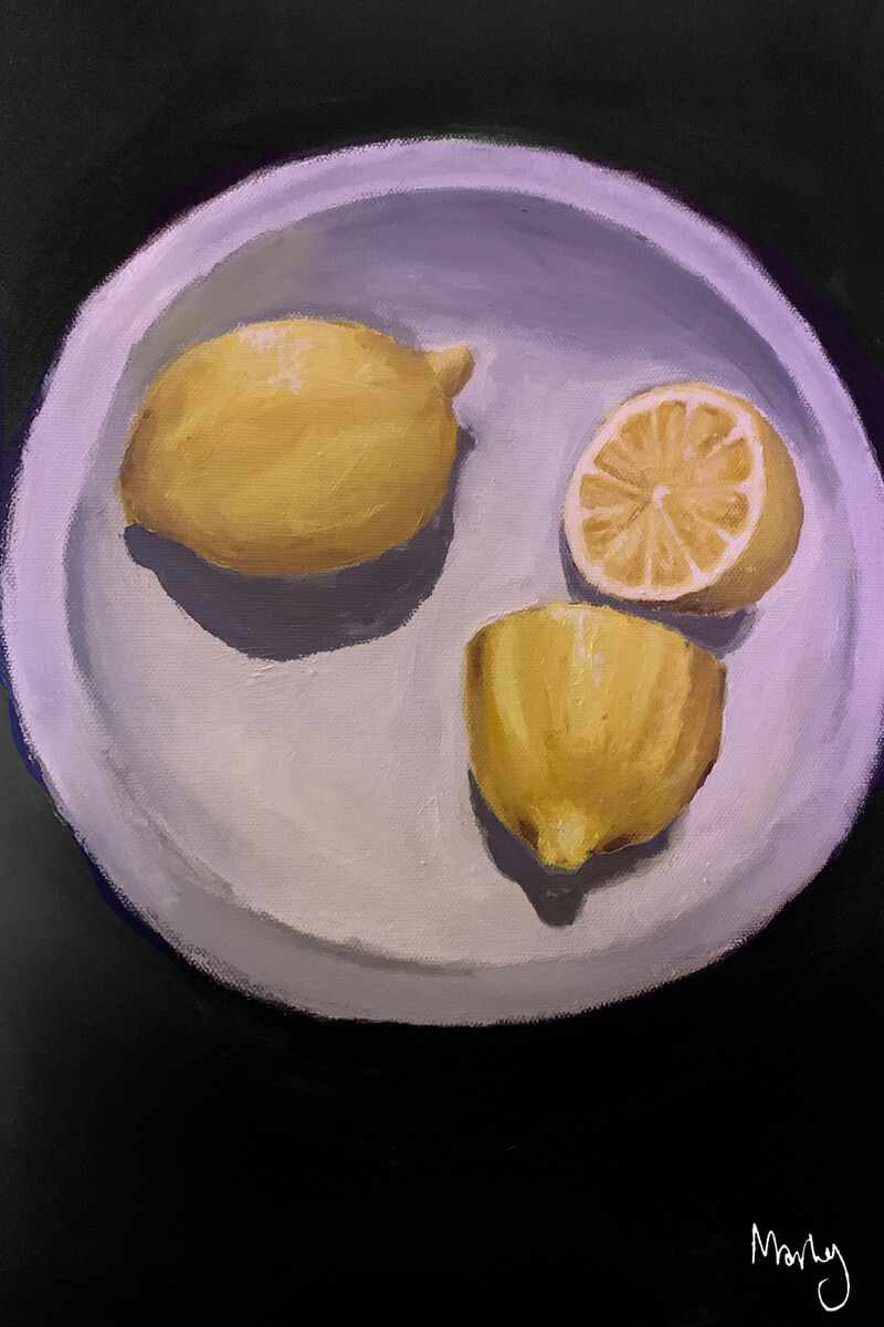 lemons on a white plate, one sliced in half.